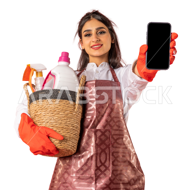 Portrait of an Arab woman wearing an apron and gloves, holding a mobile phone in her hand, showing a blank black screen, showing an application for mobile