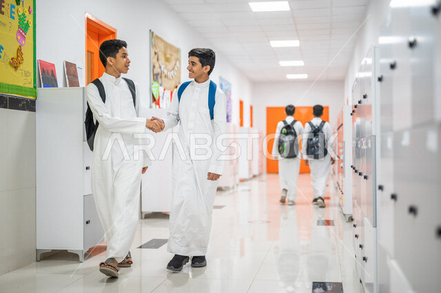 طالبان عربيان خليجيان سعوديان يتصافحان، تعارف وصداقات، العلاقات المترابطة، محبة وترابط ، لقاء و تواصل، ايماءات وجه مبتسمة، المشي في ممرات المدرسة، العودة إلى المدارس، التعليم في المملكة العربية السعودية