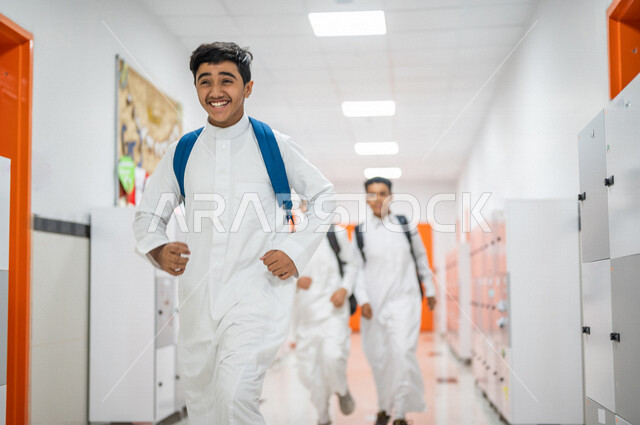 مجموعة من الطلاب العرب الخليجيين السعوديين يتجولون داخل المدرسة، ايماءات وجه مبتسمة، الجري في ممرات المدرسة، العودة إلى المدارس، التعليم في المملكة العربية السعودية
