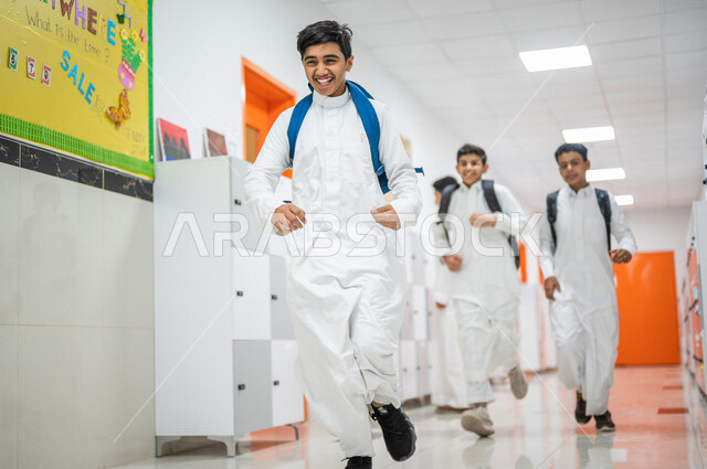 مجموعة من الطلاب العرب الخليجيين السعوديين يتجولون داخل المدرسة، ايماءات وجه مبتسمة، الجري في ممرات المدرسة، العودة إلى المدارس، التعليم في المملكة العربية السعودية