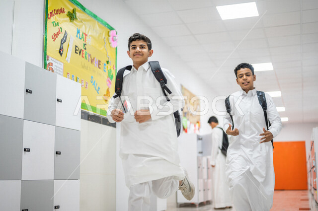 A group of Saudi Gulf Arab students wandering around the school, smiling face gestures, running in the school corridors, back to school, education in the Kingdom of Saudi Arabia