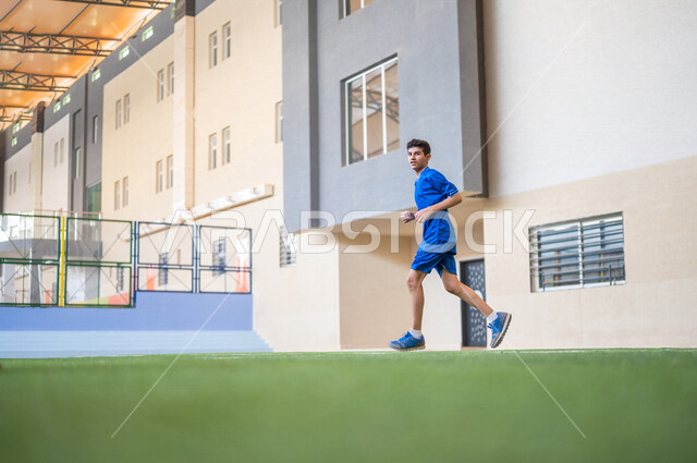 A Saudi Arab Gulf student performing warm-up exercises, running in the school playground, exercising, physical education class, education in the Kingdom of Saudi Arabia