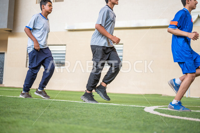 Saudi Gulf Arab students performing warm-up exercises, running in the school playground, exercising, physical education class, education in the Kingdom of Saudi Arabia