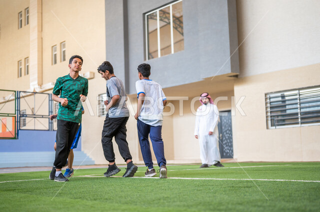 طلاب عرب خليجيين سعوديين يقومون باداء تمارين الاحماء، الجري في ملعب المدرسة، ممارسة التمارين الرياضية، حصة التربية الرياضية، التعليم في المملكة العربية السعودية