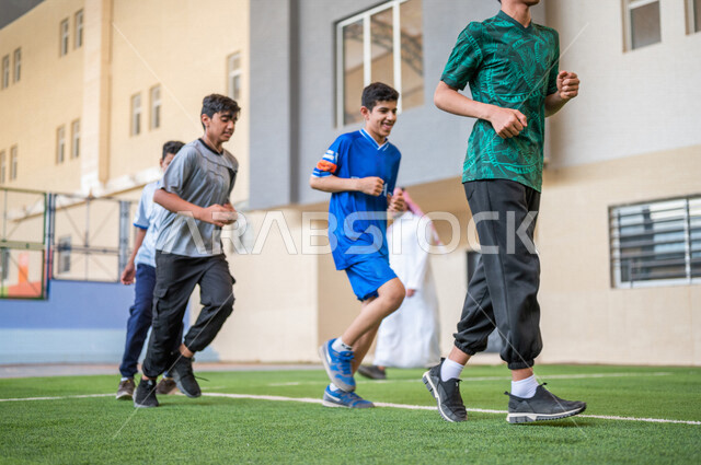 Saudi Gulf Arab students performing warm-up exercises, running in the school playground, exercising, physical education class, education in the Kingdom of Saudi Arabia