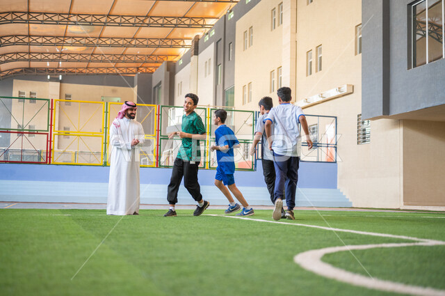 طلاب عرب خليجيين سعوديين يقومون باداء تمارين الاحماء، الجري في ملعب المدرسة، ممارسة التمارين الرياضية، حصة التربية الرياضية، التعليم في المملكة العربية السعودية