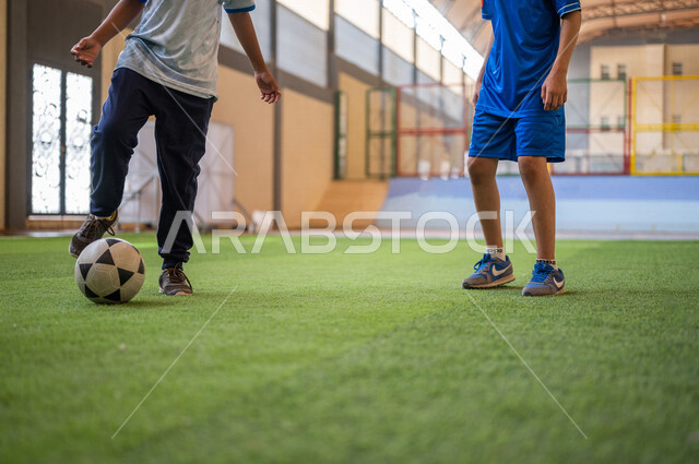 Saudi Gulf Arab students playing football in the school playground, exercising, playing football, dribbling and controlling the ball, physical education class, education in the Kingdom of Saudi Arabia