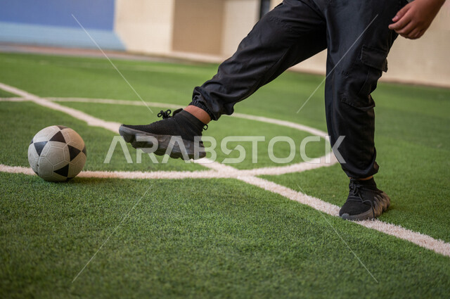 A Saudi Arab Gulf student playing football in the school playground, exercising, playing football, dribbling and controlling the ball, physical education class, education in the Kingdom of Saudi Arabia