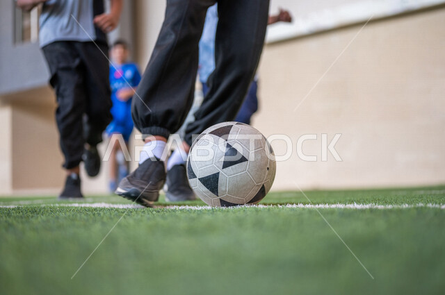 Saudi Gulf Arab students playing football in the school playground, exercising, playing football, dribbling and controlling the ball, physical education class, education in the Kingdom of Saudi Arabia