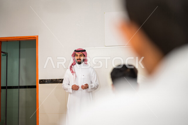 معلم عربي خليجي سعودي يقوم بشرح الدرس للطلاب، لوحة مدرسية بيضاء، المشاركة الفعالة للطلاب، التعليم الفعال، أهداف التربية والتعليم، التفاعل والمشاركة داخل الفصل الدراسي، التعليم في المملكة العربية السعودية