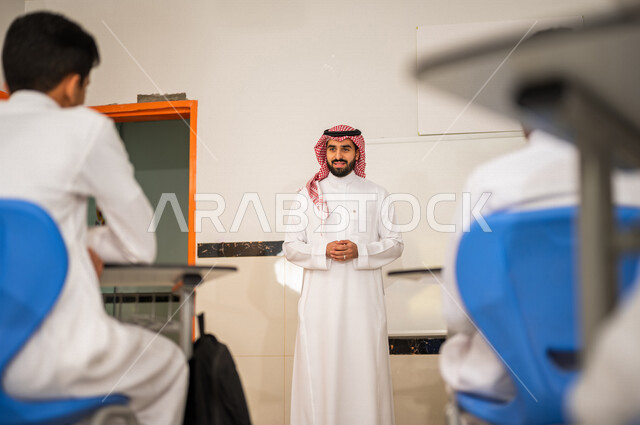 معلم عربي خليجي سعودي يقوم بشرح الدرس للطلاب، لوحة مدرسية بيضاء، المشاركة الفعالة للطلاب، التعليم الفعال، أهداف التربية والتعليم، التفاعل والمشاركة داخل الفصل الدراسي، التعليم في المملكة العربية السعودية