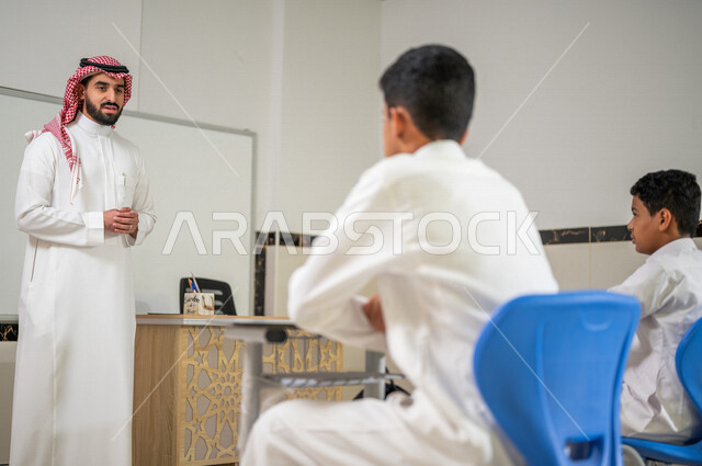 معلم عربي خليجي سعودي يقوم بشرح الدرس للطلاب، لوحة مدرسية بيضاء، المشاركة الفعالة للطلاب، التعليم الفعال، أهداف التربية والتعليم، التفاعل والمشاركة داخل الفصل الدراسي، التعليم في المملكة العربية السعودية