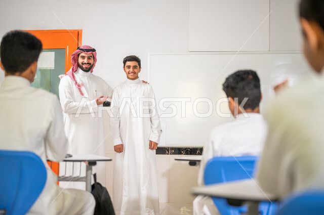 A Saudi Arabian Gulf teacher welcomes a new student, introduces students to their new classmate, welcomes new students, active participation of students, effective teaching, goals of education, happy face gestures, education in Saudi Arabia