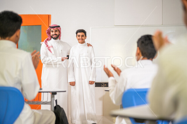 A Saudi Arabian Gulf teacher welcomes a new student, introduces students to their new classmate, welcomes new students, active participation of students, effective teaching, goals of education, happy face gestures, education in Saudi Arabia