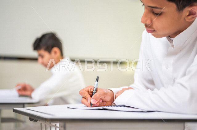 A close-up of a Saudi Arabian Gulf student solving lesson questions, active participation of students, effective teaching, education goals, interaction and participation in the classroom, education in Saudi Arabia