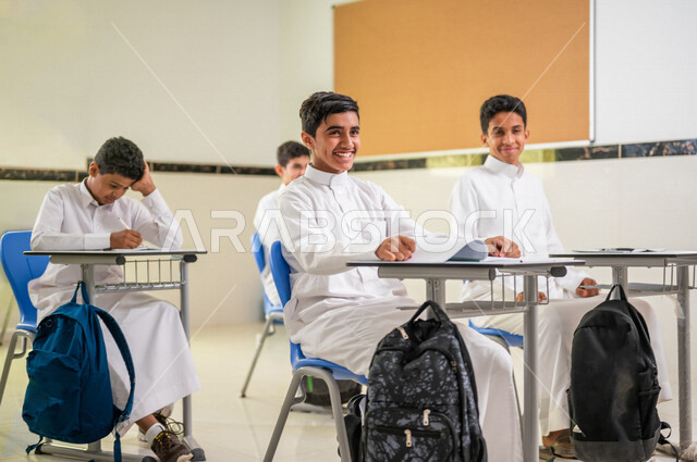 مجموعة من الطلاب العرب الخليجيين السعوديين يتفاعلون في الحصة الدراسية، المشاركة الفعالة للطلاب، التعليم الفعال، أهداف التربية والتعليم، التفاعل والمشاركة داخل الفصل الدراسي، ايماءات وجه تدل على السعادة، التعليم في السعودية