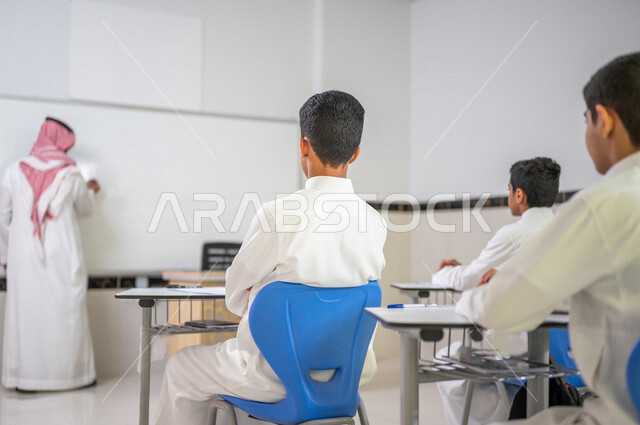 معلم عربي خليجي سعودي يقوم بشرح الدرس الدرس للطلاب، استخدام اللوحة المدرسية البيضاء، المشاركة الفعالة للطلاب، التعليم الفعال، أهداف التربية والتعليم، التفاعل والمشاركة داخل الفصل الدراسي، التعليم في السعودية