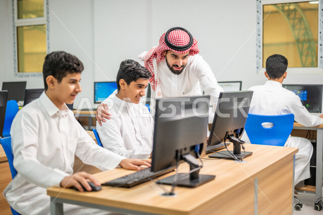 معلم عربي خليجي سعودي في معمل الحاسب الآلي، تعليم الطلبة كيفية استخدام الكمبيوتر في المدرسة، استخدام لوحة المفاتيح للكتابة، التعليم الالكتروني، المناهج المطورة، المشاركة الفعالة للطلاب، التعليم الفعال، التعليم في المملكة العربية السعودية