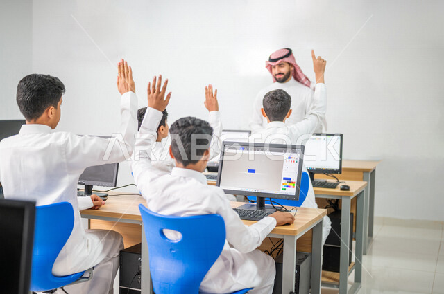 معلم عربي خليجي سعودي في معمل الحاسب الآلي، تعليم الطلبة كيفية استخدام الكمبيوتر في المدرسة، استخدام لوحة المفاتيح للكتابة، التعليم الالكتروني، المناهج المطورة، المشاركة الفعالة للطلاب، التعليم الفعال، التفاعل والمشاركة داخل الفصل الدراسي، التعليم في السع