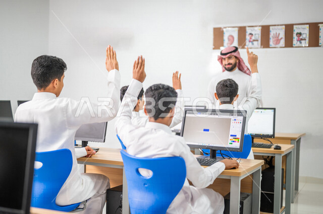 A group of Saudi Gulf Arab students interacting in the classroom by raising their hands to answer the teacher's questions, active participation of students, effective teaching, goals of education, interaction and participation in the classroom, education 