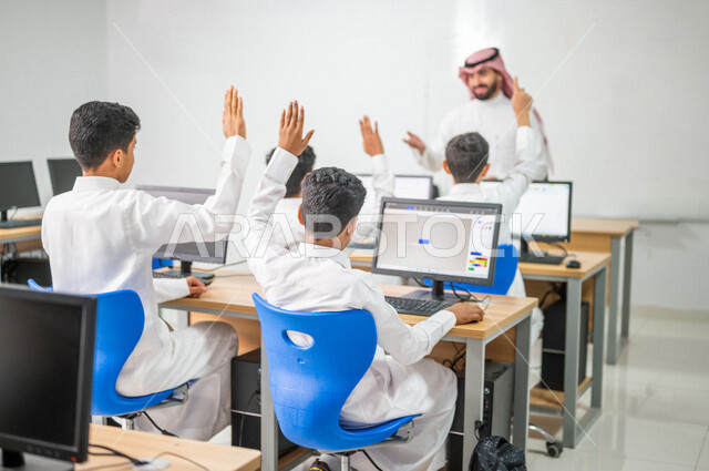 معلم عربي خليجي سعودي في معمل الحاسب الآلي، تعليم الطلبة كيفية استخدام الكمبيوتر في المدرسة، استخدام لوحة المفاتيح للكتابة، التعليم الالكتروني، المناهج المطورة، المشاركة الفعالة للطلاب، التعليم الفعال، التفاعل والمشاركة داخل الفصل الدراسي، التعليم في السع
