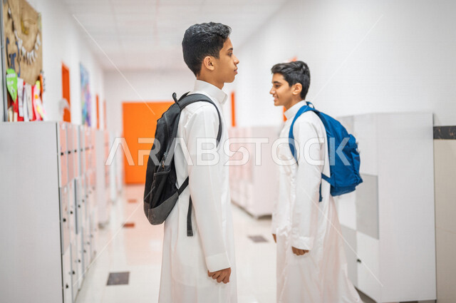 طالبان عربيان خليجيان سعوديان يقفان في ممر المدرسة، التجول في ممرات المدرسة، العودة إلى المدارس، التعليم في المملكة العربية السعودية