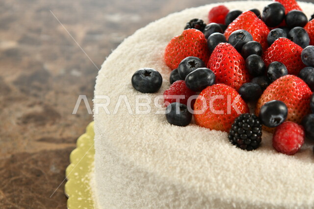 صورة مقربة لقالب الكيك الهش واللذيذ , تزيين الكيك بالفواكه البرية الطازجة , كيكة هشة غنية بالكريمة , كرم الضيافة , مخبوزات طازجة , كعك العيد . 