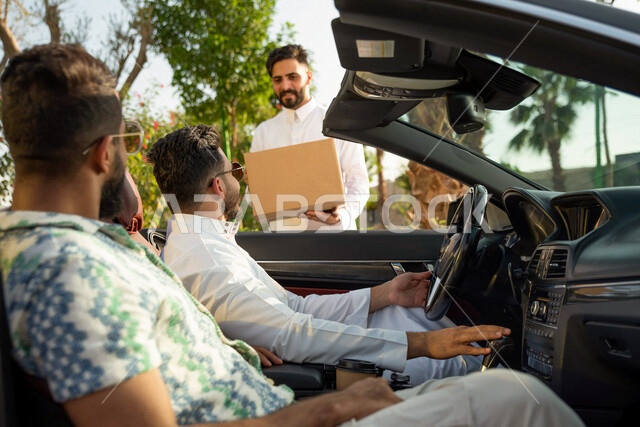 صوره مقربه لمجموعه من الشباب العرب السعوديون الخليجيون في رحلة بالسيارة، شراء الأغراض من الطريق, توصيل البضائع الى السياره, طلبات السيارات, سياره كشف فاخره, التنزه في شوارع المملكه، رحله شبابيه في السياره، قضاء وقت ممتع مع الأصدقاء، تسليه وترفيه