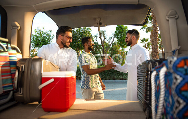 مجموعه من الشباب العرب السعوديون الخليجيون يقومون بالتجهيز لرحله شبابيه ممتعه, رحلة بريه, تجهيز الأمتعه والحقائب, سياحه وسفر, السفر عن طريق السياره, إيماءات تدل على السعاده  
