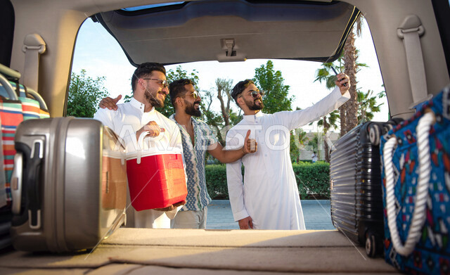 مجموعه من الشباب العرب السعوديون الخليجيون يقومون بالتجهيز لرحله شبابيه ممتعه, إلتقاط صور تذكاريه عبر الهاتف المحمول, رحلة بريه, تجهيز الأمتعه والحقائب, سياحه وسفر, السفر عن طريق السياره, إيماءات تدل على السعاده  