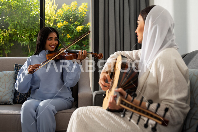 صديقات عربيات خليجيات سعوديات يجلسن في المنزل، العزف على آلة الكمان وآلة العود، قضاء أوقات ممتعة مع الأصدقاء، جلسة وناسة وطرب، مواهب فنية، الفنون الموسيقية، إجتماع الأصدقاء في المنزل، آلات موسيقية، أنشطة ترفيهية، زيارات الأهل والأقارب
