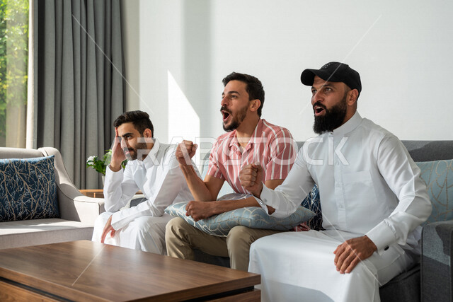 مجموعة من الأصدقاء العرب السعوديين يجلسون في المنزل، تعابير تدل على التشجيع والإندماج، قضاء أوقات ممتعة مع الأصدقاء، أنشطة ترفيهية، زيارات الأهل والأقارب، أندية وتشجيع، مشاهدة المباريات