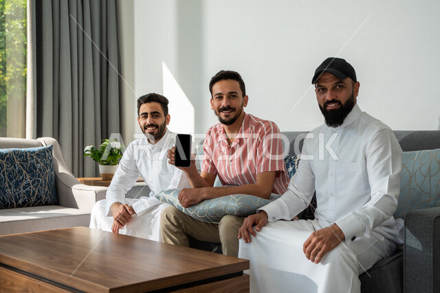 مجموعة من الأصدقاء العرب السعوديين يجلسون في المنزل،عرض شاشة سوداء فارغة، عرض خدمات وتطبيقات عبر الجوال، جلسة وناسة وتعارف، إجتماع الأصدقاء في المنزل، زيارات الأهل والأقارب، التسويق الرقمي الإلكتروني