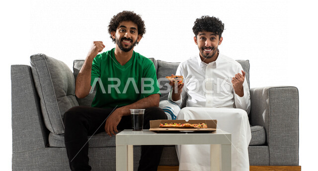 بورتريه لشابان عربيان خليجيان سعوديان يشجعان منتخب السعودية لكرة القدم، متابعة مباراة كرة القدم، شاب يرتدي تيشرت اخضر، الاستمتاع باكل البيتزا، النجاح والقوة، ايماءات وجه ويدين تدل على التشجيع والحماس، كأس العالم 2022، مونديال قطر، خلفية بيضاء