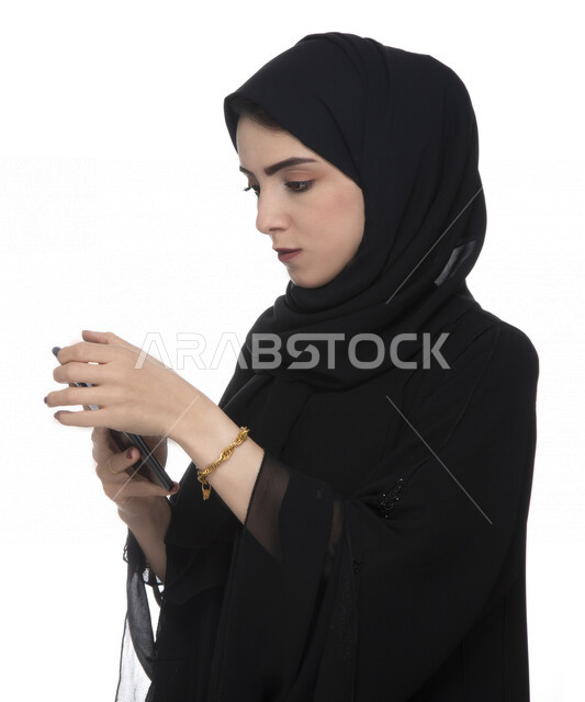 بورتريه لسيدة أعمال عربية خليجية إماراتية  ، تستخدام الهاتف المحمول بإيماءات وجه تدل على التركيز , العمل عن بعد، مفهوم إستخدام التكنلوجيا وأجهزة التقنية الحديثة، التسلية والترفيه، حجز طلبات الأونلاين ، التسويق الإلكتروني، عقد صفقات عبر الجوال , خلفيةبيضاء
