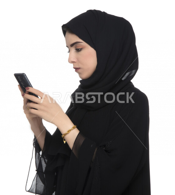 بورتريه لسيدة أعمال عربية خليجية إماراتية  ، تستخدام الهاتف المحمول بإيماءات وجه تدل على التركيز , العمل عن بعد، مفهوم إستخدام التكنلوجيا وأجهزة التقنية الحديثة، التسلية والترفيه، حجز طلبات الأونلاين ، التسويق الإلكتروني، عقد صفقات عبر الجوال , خلفيةبيضاء