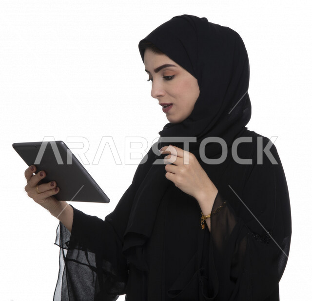 بورتريه لإمرأة عربيه خليجيه إماراتية بالزي التقليدي تستخدم جهاز لوحي  ، التسويق الإلكتروني ، مفهوم التكنولوجيا وإستخدام الأجهزة التقنية الحديثة ، العمل عن بعد  , مكالمة فيديو , مشاهدة البرامج , خلفية بيضاء 