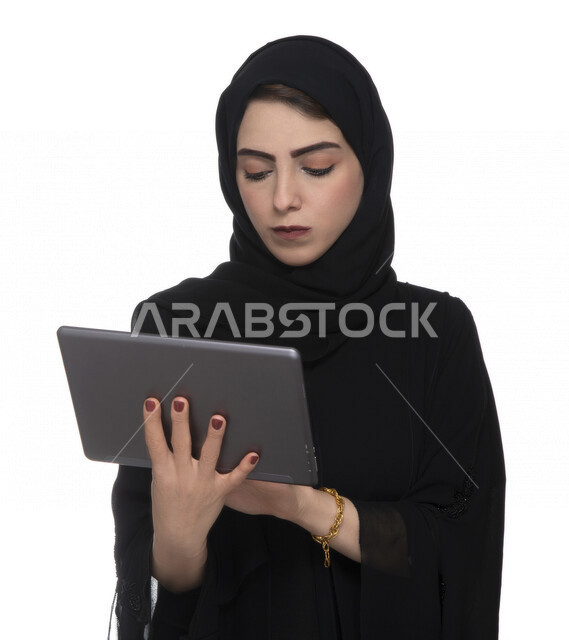 بورتريه لإمرأة عربيه خليجيه إماراتية بالزي التقليدي تستخدم جهاز لوحي  ، التسويق الإلكتروني ، مفهوم التكنولوجيا وإستخدام الأجهزة التقنية الحديثة ، العمل عن بعد  , مكالمة فيديو , مشاهدة البرامج , خلفية بيضاء 