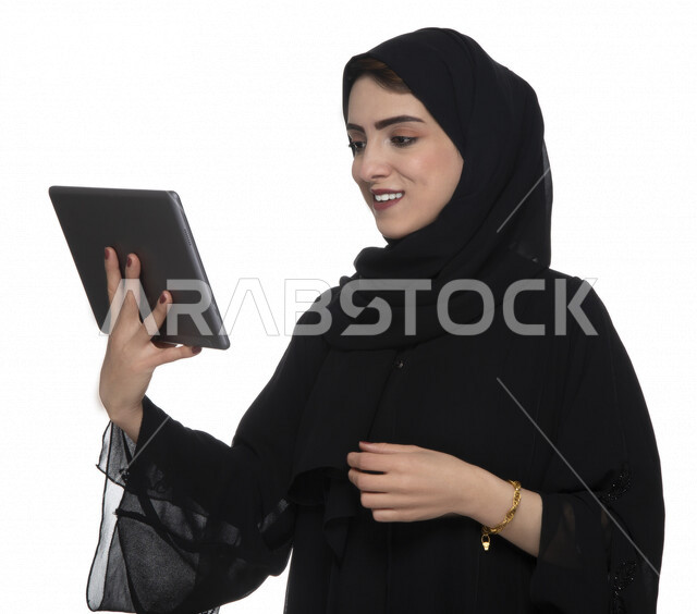 بورتريه لإمرأة عربيه خليجيه إماراتية بالزي التقليدي تستخدم جهاز لوحي  ، التسويق الإلكتروني ، مفهوم التكنولوجيا وإستخدام الأجهزة التقنية الحديثة ، العمل عن بعد  , مكالمة فيديو , مشاهدة البرامج , خلفية بيضاء 