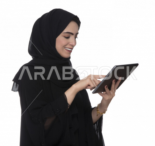 بورتريه لإمرأة عربيه خليجيه إماراتية بالزي التقليدي تستخدم جهاز لوحي بإيماءات وجه تدل على الفرح ,  ، التسويق الإلكتروني ، مفهوم التكنولوجيا وإستخدام الأجهزة التقنية الحديثة ، العمل عن بعد  , مكالمة فيديو , مشاهدة البرامج , خلفية بيضاء 