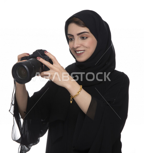 بورتريه لشابه عربيه خليجيه إماراتيه ، تحمل بيدها كاميرة التصوير ، تلتقط الصور باستخدام كاميرا التصوير ، التصوير الفوتوغرافي ، موهبة واحتراف فن التصوير ، مصوره إماراتية  ، كاميرا عالية الدقة ، خلفية بيضاء 