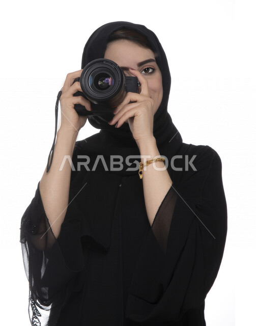 بورتريه لشابه عربيه خليجيه إماراتيه ، تحمل بيدها كاميرة التصوير ، تلتقط الصور باستخدام كاميرا التصوير ، التصوير الفوتوغرافي ، موهبة واحتراف فن التصوير ، مصوره إماراتية  ، كاميرا عالية الدقة ، خلفية بيضاء 