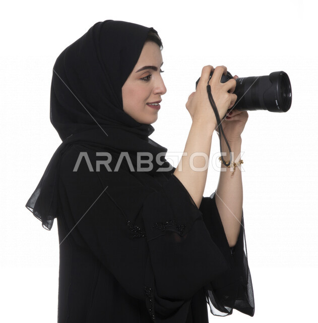 بورتريه لشابه عربيه خليجيه إماراتيه ، تحمل بيدها كاميرة التصوير ، تلتقط الصور باستخدام كاميرا التصوير ، التصوير الفوتوغرافي ، موهبة واحتراف فن التصوير ، مصوره إماراتية  ، كاميرا عالية الدقة ، خلفية بيضاء 