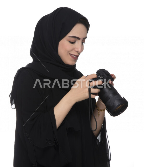 بورتريه لشابه عربيه خليجيه إماراتيه ، تحمل بيدها كاميرة التصوير ، تلتقط الصور باستخدام كاميرا التصوير ، التصوير الفوتوغرافي ، موهبة واحتراف فن التصوير ، مصوره إماراتية  ، كاميرا عالية الدقة ، خلفية بيضاء 