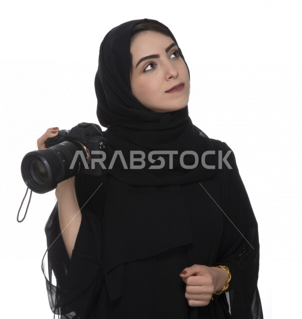 بورتريه لشابه عربيه خليجيه إماراتيه ، تحمل بيدها كاميرة التصوير  بإيماءات وجه تدل على التأمل ,لتقط الصور باستخدام كاميرا التصوير ، التصوير الفوتوغرافي ، موهبة واحتراف فن التصوير ، مصوره إماراتية  ، كاميرا عالية الدقة ، خلفية بيضاء 