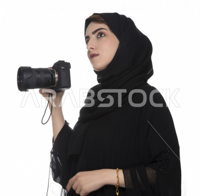 بورتريه لشابه عربيه خليجيه إماراتيه ، تحمل بيدها كاميرة التصوير  بإيماءات وجه تدل على التأمل ,لتقط الصور باستخدام كاميرا التصوير ، التصوير الفوتوغرافي ، موهبة واحتراف فن التصوير ، مصوره إماراتية  ، كاميرا عالية الدقة ، خلفية بيضاء 