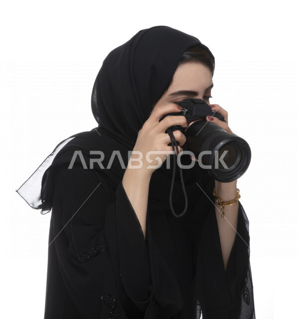بورتريه لشابه عربيه خليجيه إماراتيه ، تحمل بيدها كاميرة التصوير ، تلتقط الصور باستخدام كاميرا التصوير ، التصوير الفوتوغرافي ، موهبة واحتراف فن التصوير ، مصوره إماراتية  ، كاميرا عالية الدقة ، خلفية بيضاء 