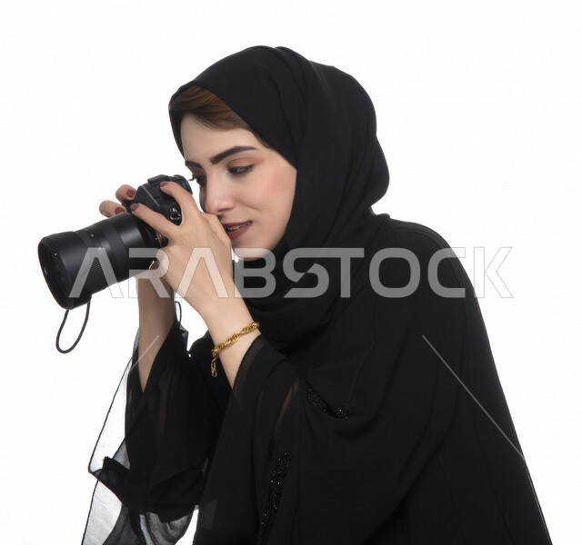 بورتريه لشابه عربيه خليجيه إماراتيه ، تحمل بيدها كاميرة التصوير ، تلتقط الصور باستخدام كاميرا التصوير ، التصوير الفوتوغرافي ، موهبة واحتراف فن التصوير ، مصوره إماراتية  ، كاميرا عالية الدقة ، خلفية بيضاء 