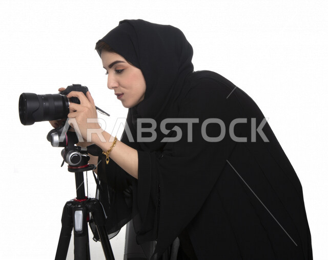 بورتريه لشابه عربيه خليجيه إماراتيه ، تحمل بيدها كاميرة التصوير ، تلتقط الصور باستخدام كاميرا التصوير ، التصوير الفوتوغرافي ، موهبة واحتراف فن التصوير ، مصوره إماراتية  ، كاميرا عالية الدقة ، خلفية بيضاء 