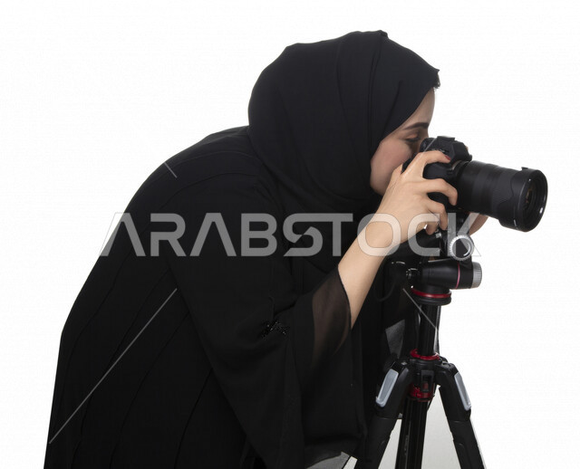 Portrait of an Arab Gulf Emirati young woman, holding a camera in her hand, taking pictures using the camera, photography, talent and professionalism in the art of photography, Emirati photographer, high-resolution camera, white background